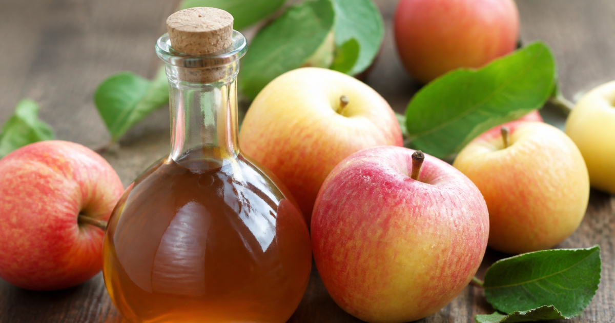 Bouteille de vinaigre brun aupres de pommes fraiches
