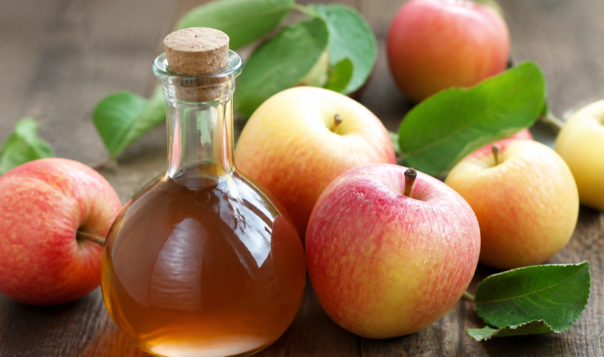 Bouteille de vinaigre brun aupres de pommes fraiches