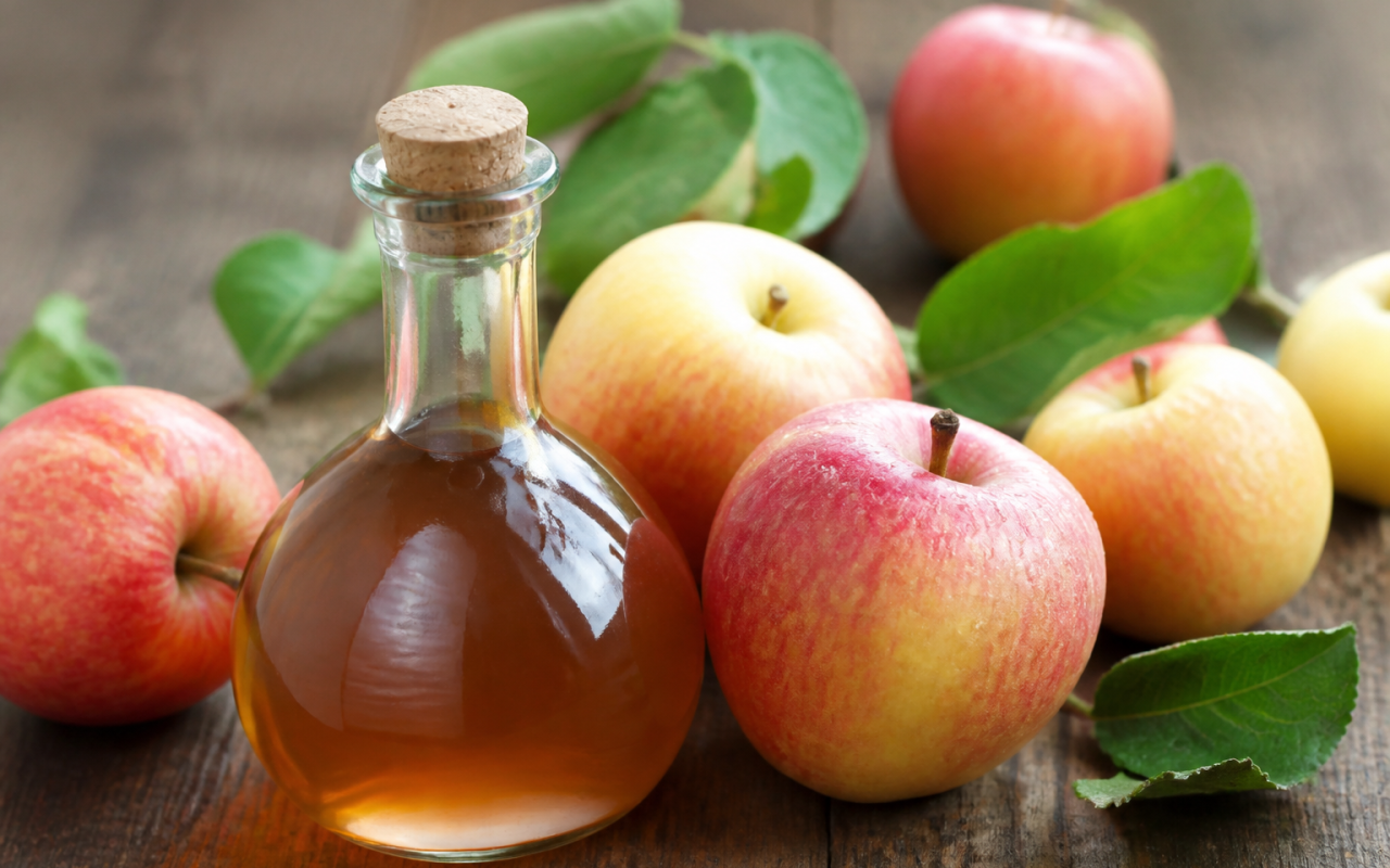 Bouteille de vinaigre brun aupres de pommes fraiches