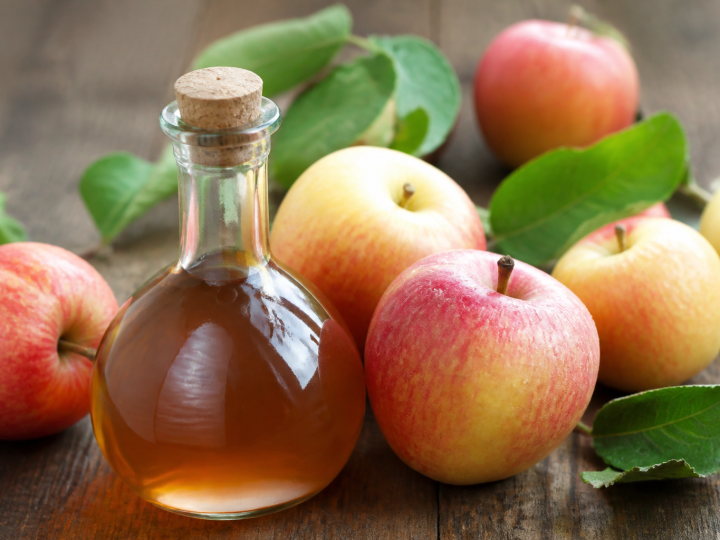 Bouteille de vinaigre brun aupres de pommes fraiches