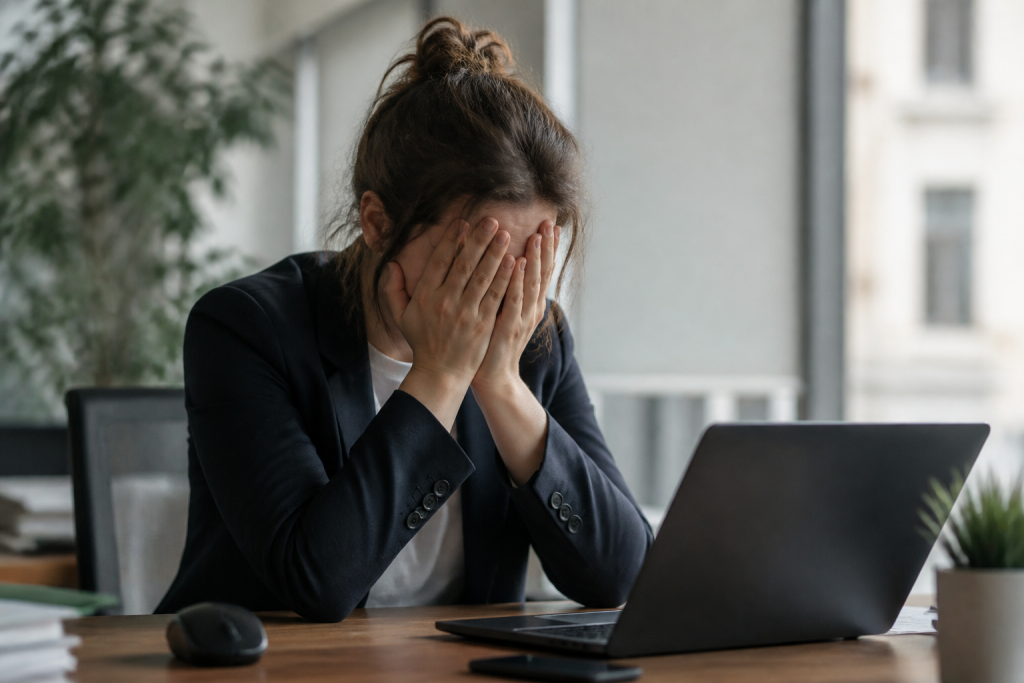 Employe fatigue assis a son bureau les mains sur le visage