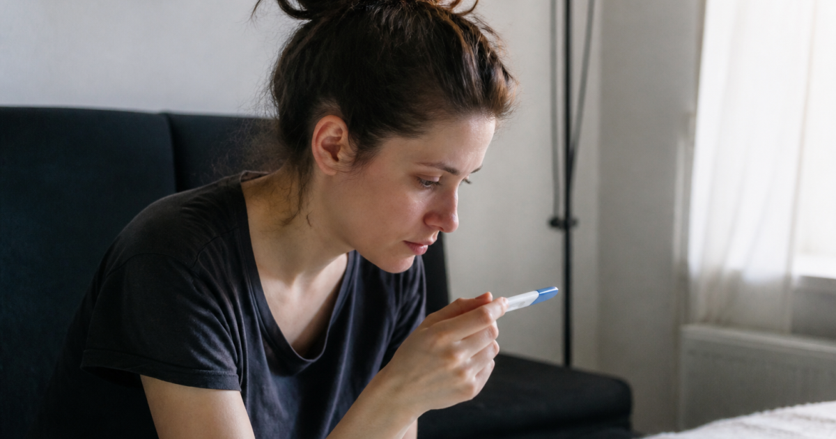 Femme assise regardant un test de grossesse positif