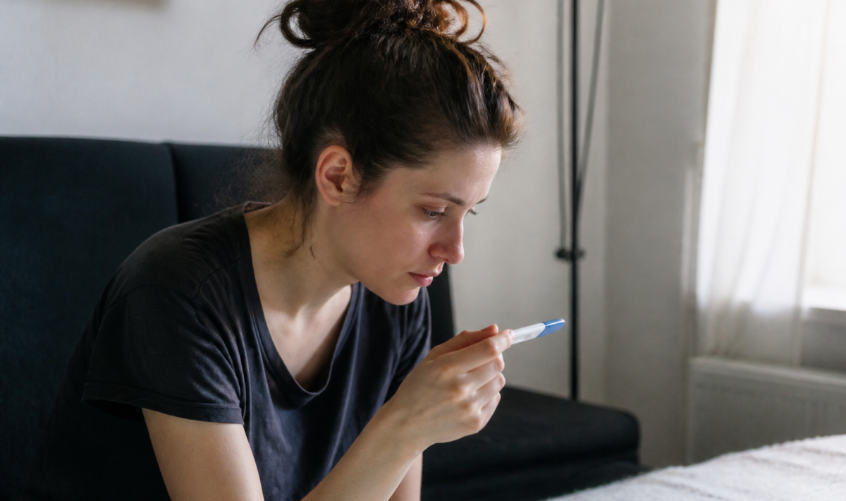 Femme assise regardant un test de grossesse positif