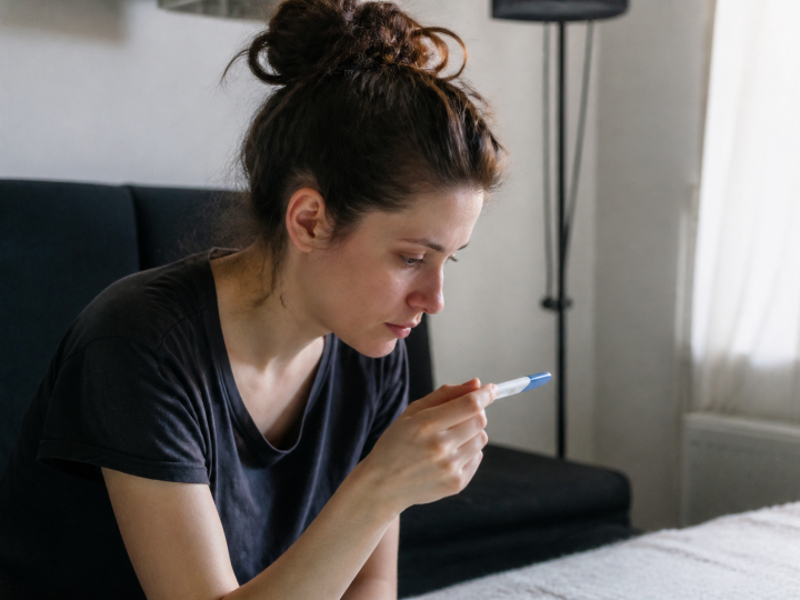 Femme assise regardant un test de grossesse positif