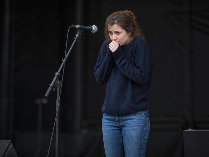 Femme tremblante devant microphone sur scene vide.