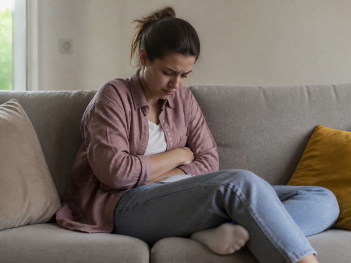 Personne assise tenant son abdomen douloureux.