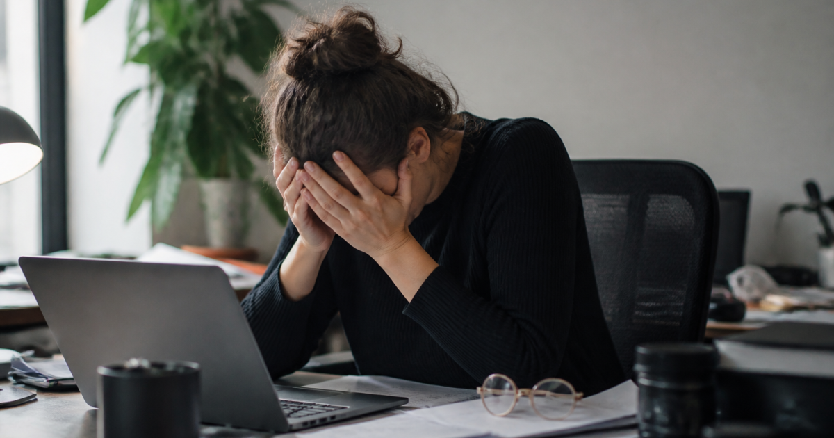 Personne epuisee assise au bureau, tete dans les mains