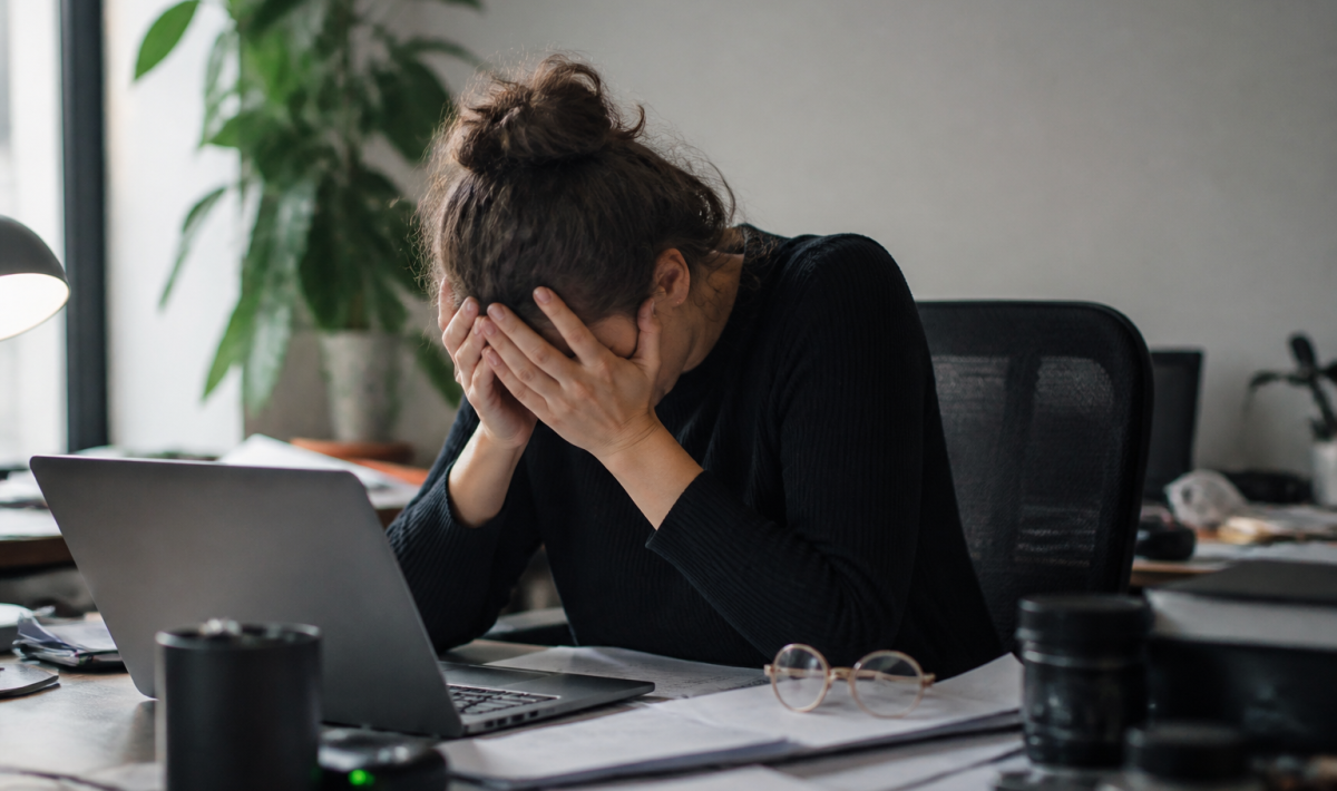 Personne epuisee assise au bureau, tete dans les mains