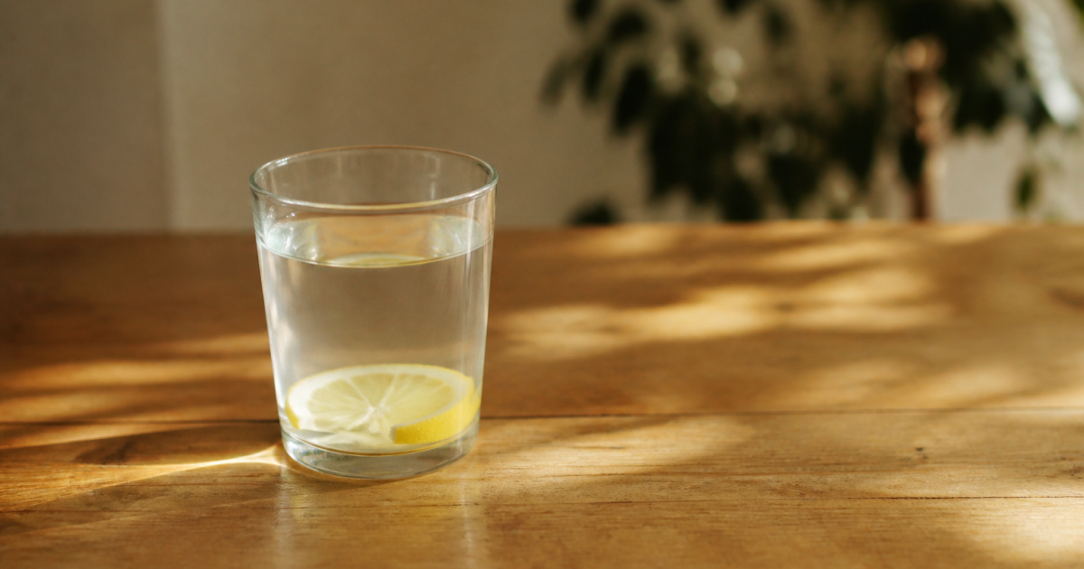 Verre d'eau citronnée posé sur table en bois