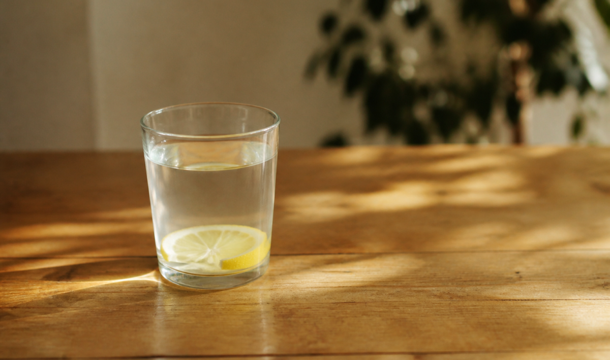 Verre d'eau citronnée posé sur table en bois