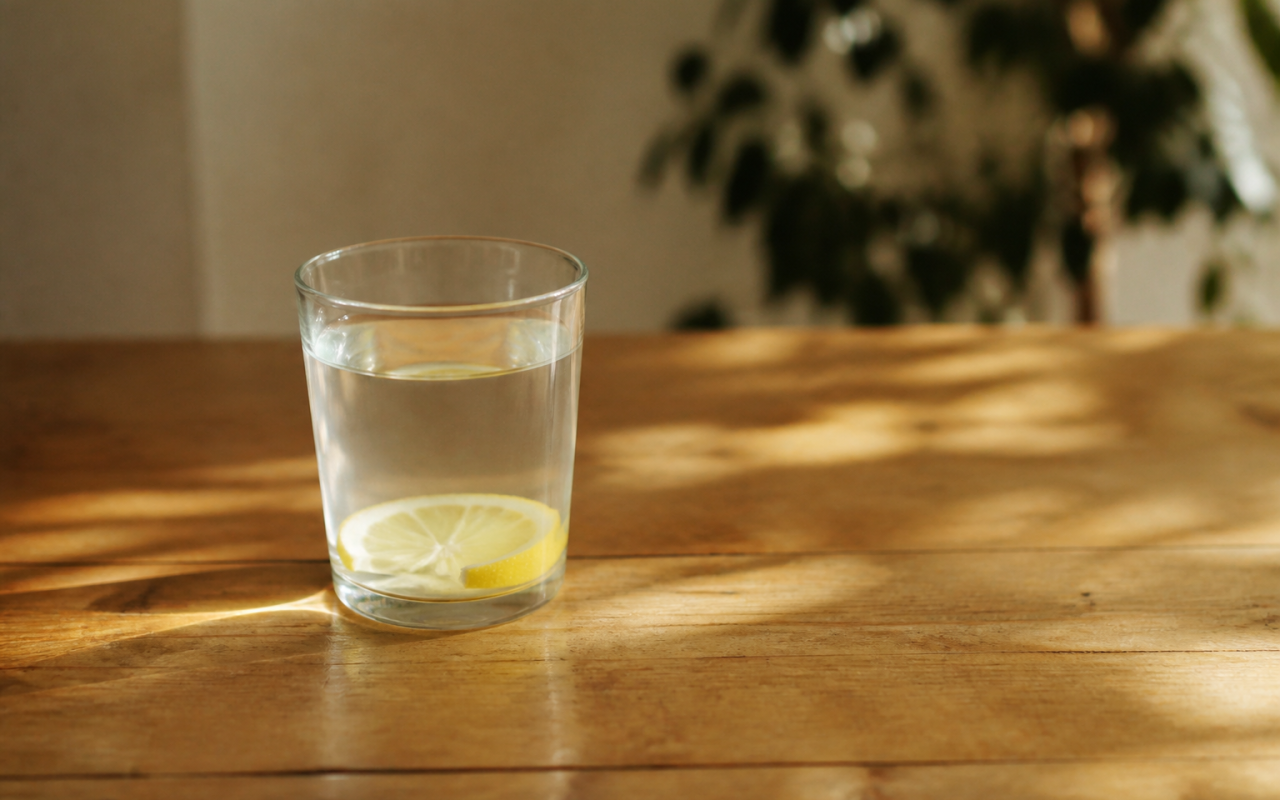 Verre d'eau citronnée posé sur table en bois