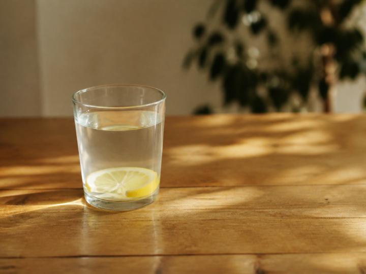 Verre d'eau citronnée posé sur table en bois