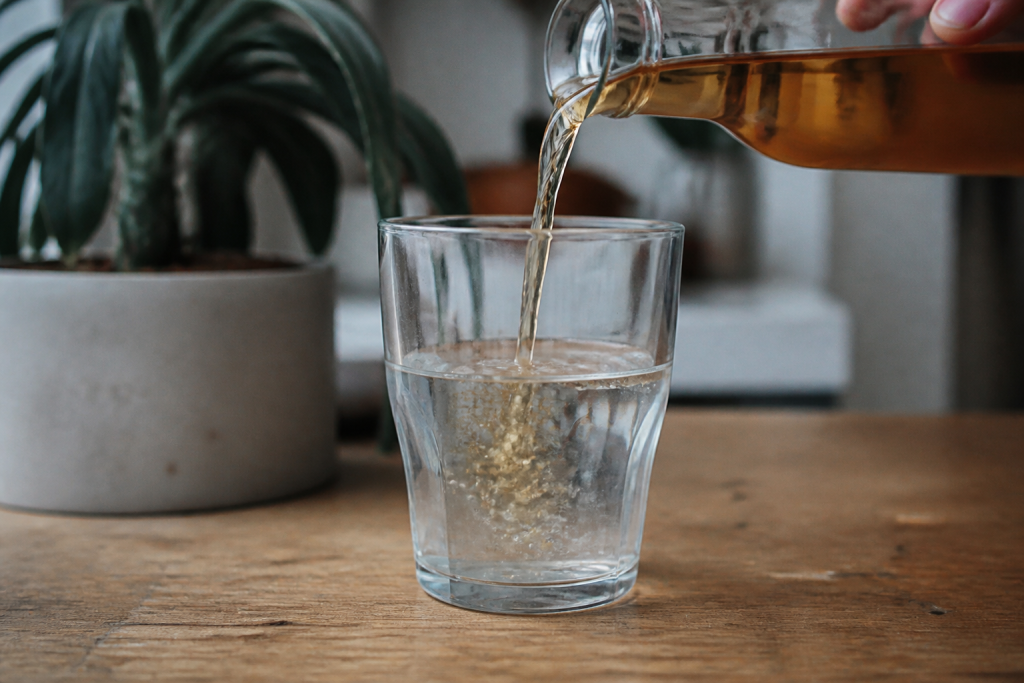 Verre d'eau claire avec vinaigre ambré versé dedans