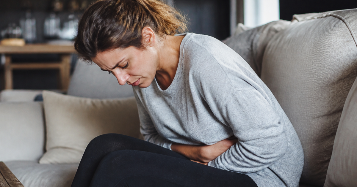 Femme assise tenant son bas-ventre en douleur