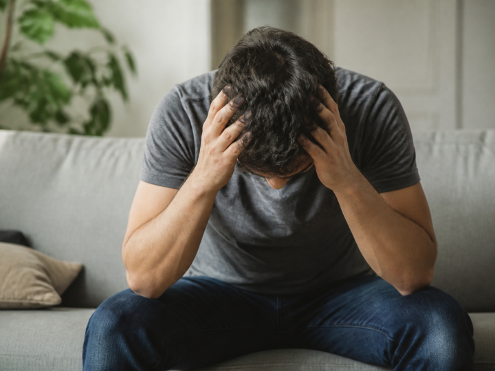Homme assis penche en avant tenant sa tete fatigue