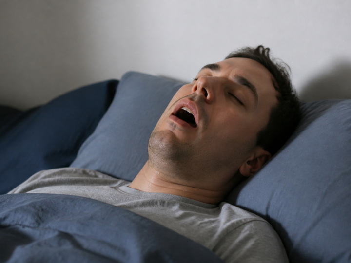 Homme allongé sur le dos ronfle la bouche ouverte pendant sommeil