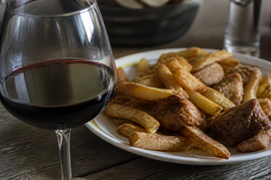 Verre de vin rouge pres d'une assiette de nourriture grasse