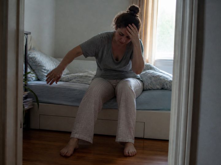 Personne se levant lentement du lit, main sur la tete, equilibre instable