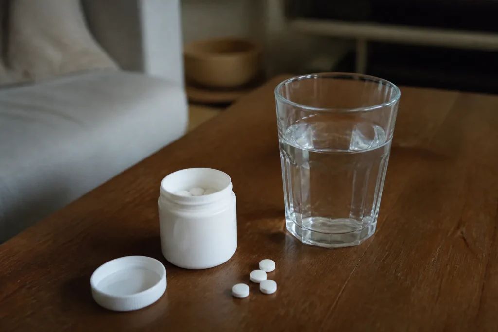 Boite de comprimes blancs et verre d'eau sur table