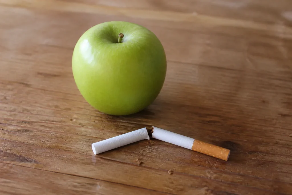 Cigarette cassee posee pres dune pomme verte sur table