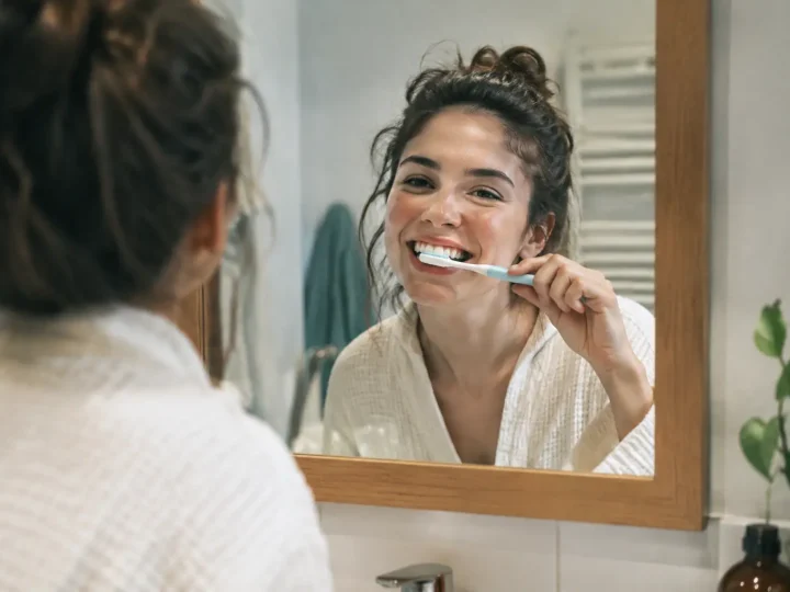 Femme souriante brossant ses dents devant le miroir
