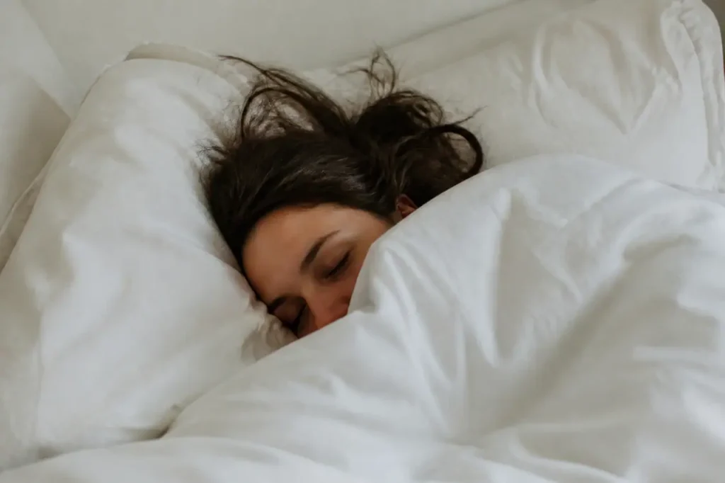 Femme dormant paisiblement sous une couette blanche