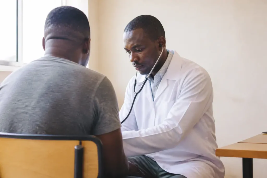 Medecin en blouse blanche examinant un patient assis