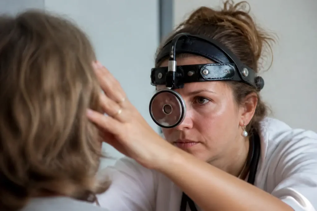 Medecin examinant un patient avec miroir frontal