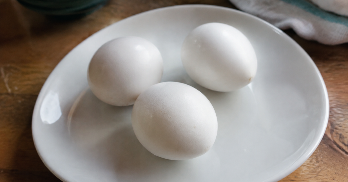 Trois oeufs cuits entiers poses sur une assiette blanche