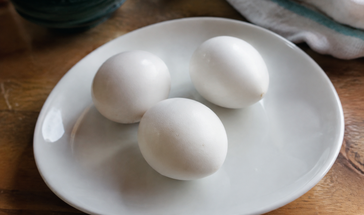 Trois oeufs cuits entiers poses sur une assiette blanche