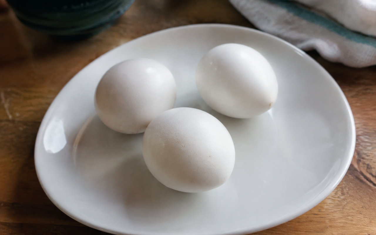 Trois oeufs cuits entiers poses sur une assiette blanche