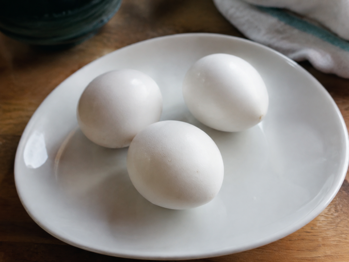 Trois oeufs cuits entiers poses sur une assiette blanche