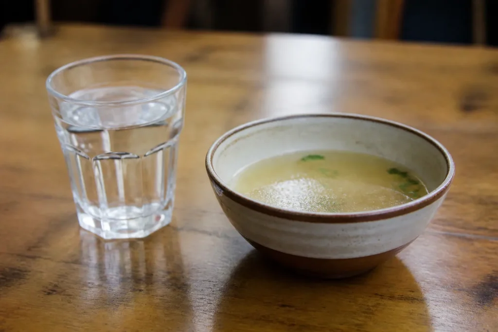 Verre d'eau et bol de bouillon sur table